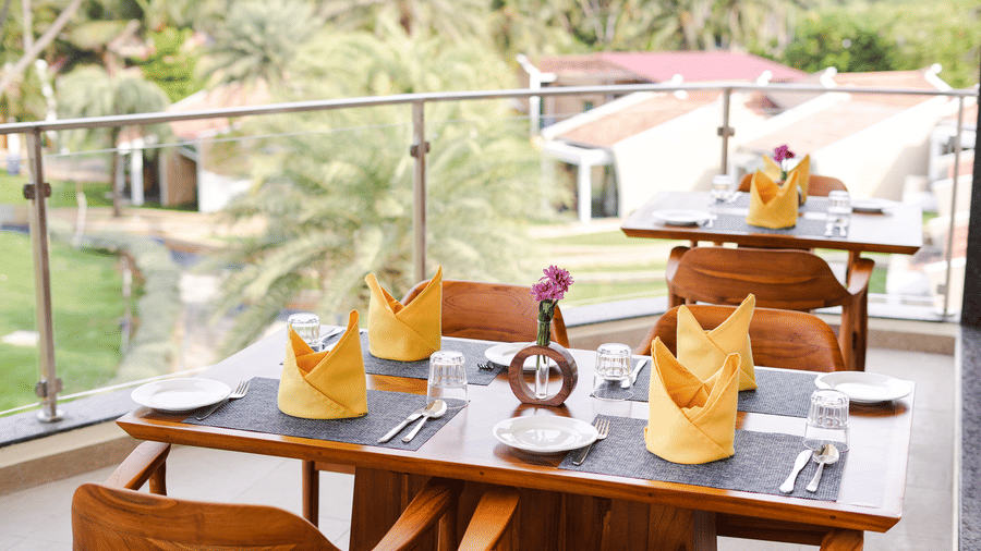 An outdoor dining area with tables and chairs, overlooking a lush green landscape - MGM Beach Resorts.